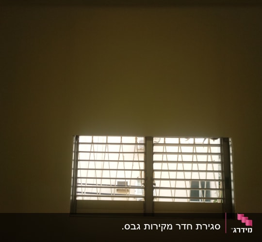 חלון עם סורגים על קיר גבס
